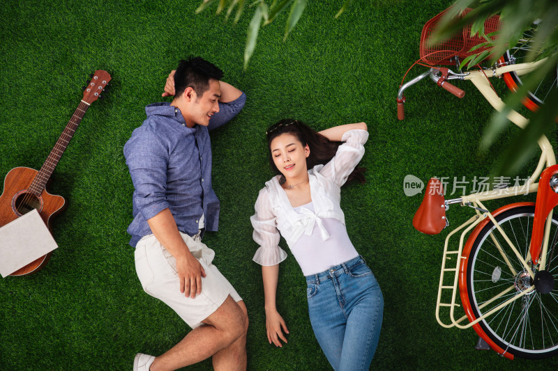 幸福的青年伴侣躺在草地上享受休闲时光