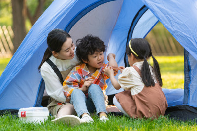 在帐篷前小女孩给小男孩处理伤口