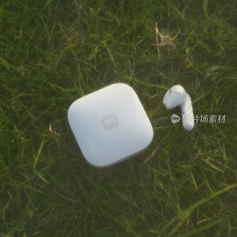 草地上的白色小米蓝牙耳机