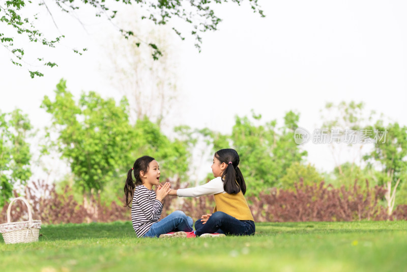 两个坐在树下玩拍手游戏的女孩