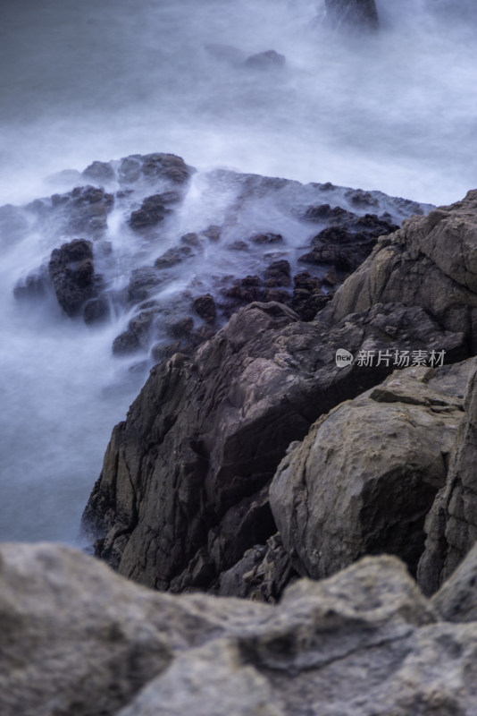 海边礁石受海浪拍打形成水雾的景象