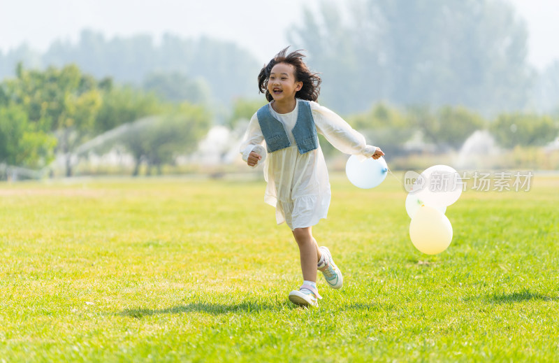 一个小女孩在草地上拿着气球奔跑