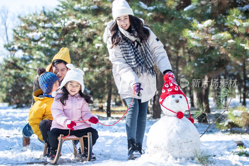 在雪地上玩雪橇的一家人