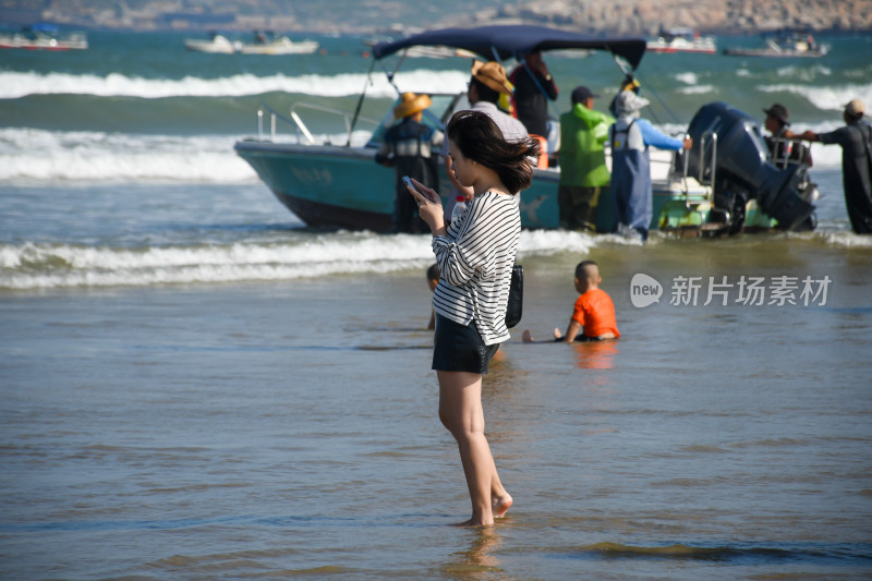 女子海边站立使用手机