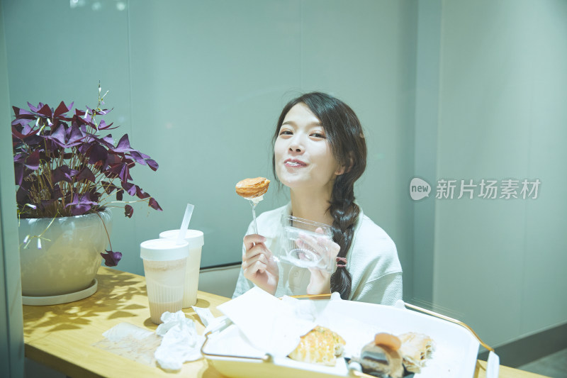 在烘焙店吃面包喝牛奶的可爱亚洲少女