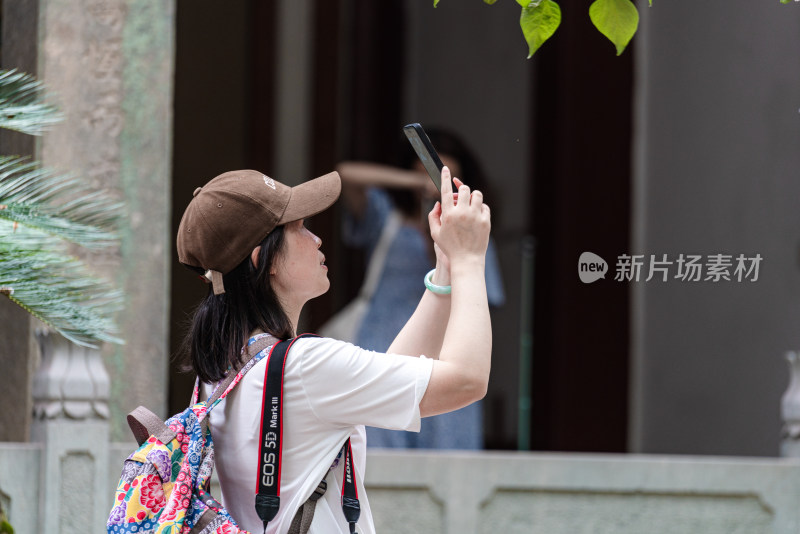 背着背包的女子用手机拍照的场景