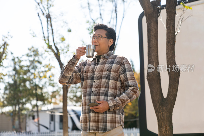 一个老年男人站在房车露营地喝咖啡