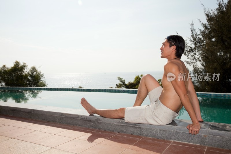 年轻男人在游泳池边休息