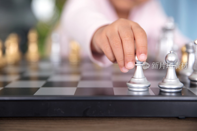 孩子的小手拿着国际象棋中的兵棋子在下棋