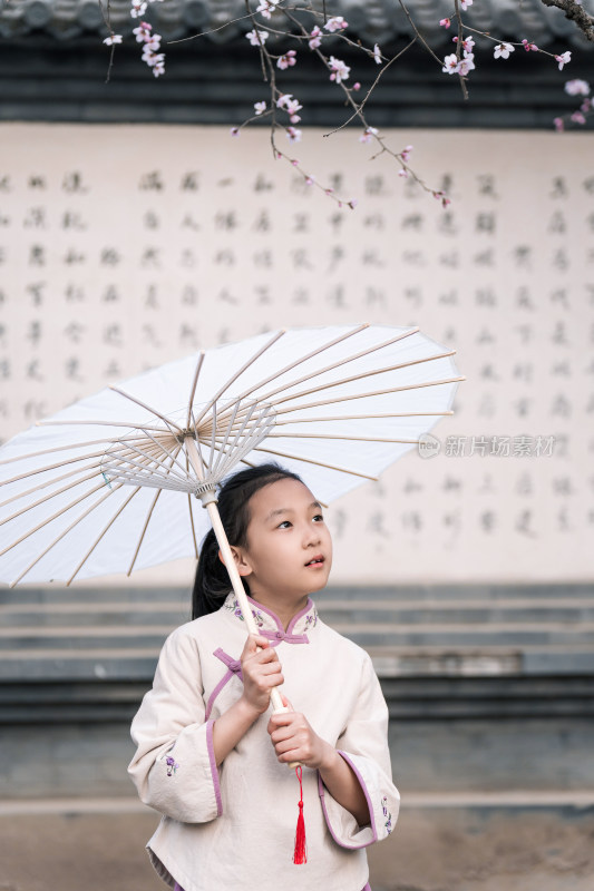 在盛开的桃花树下撑伞的中国女孩