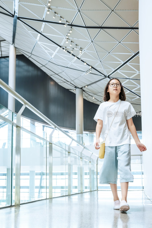 戴眼镜女孩在现代建筑内行走参观