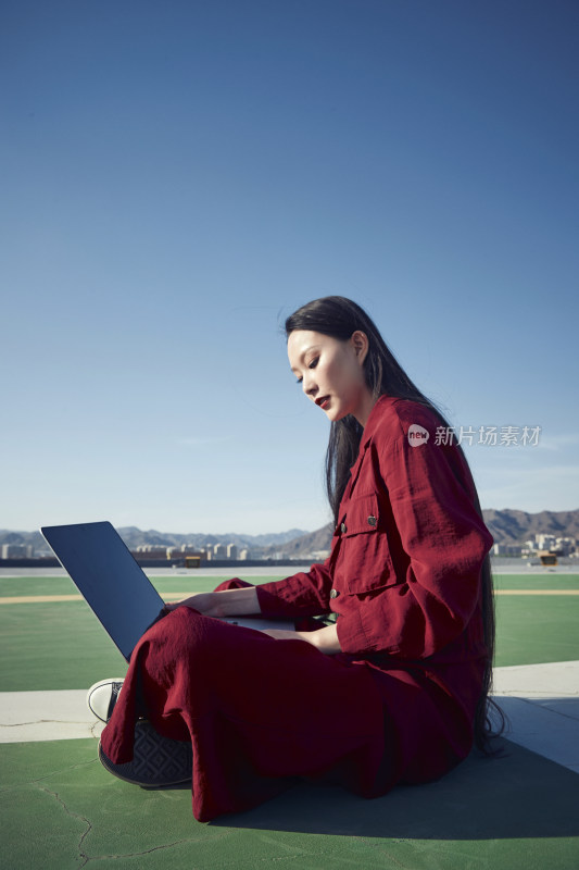 亚洲商务年轻女性在楼顶停机坪使用电脑办公