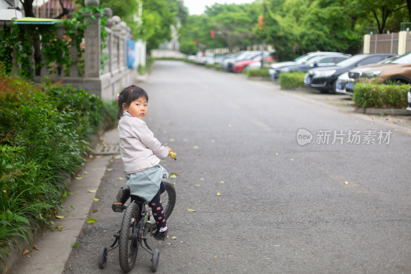 小女孩在小区里独自骑车回头看