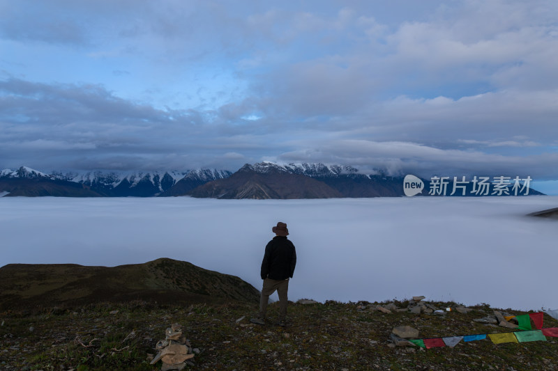 藏族男子站在山顶眺望云海和雪山