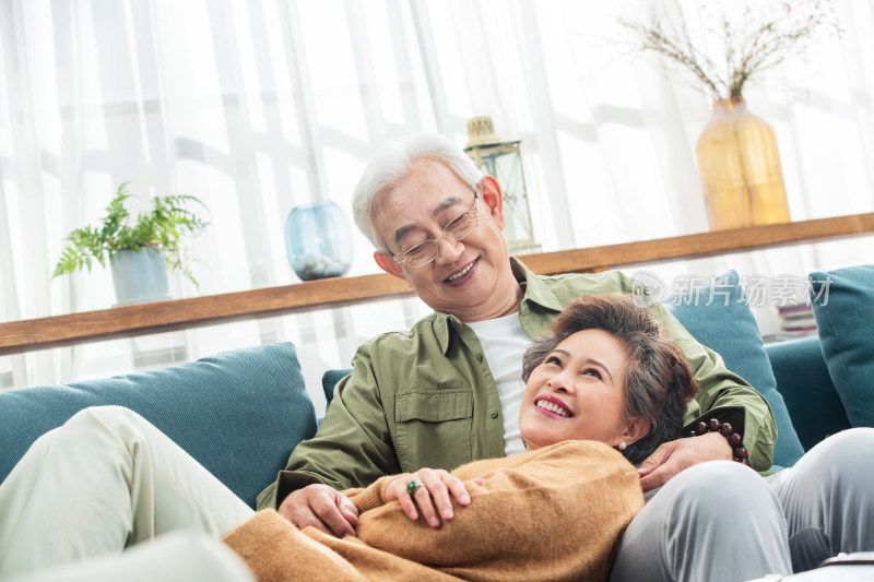 沙发上幸福的中老年女士躺在丈夫腿上