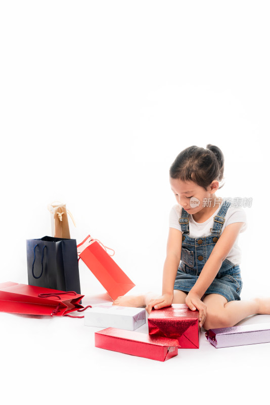 坐在白色背景前拆开礼物的中国女孩