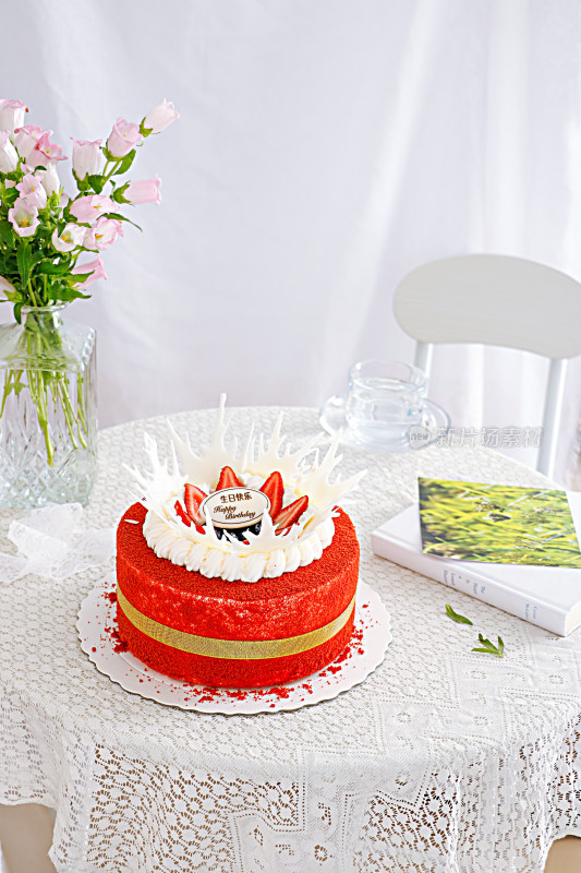 白色桌面上摆放着鲜花和生日蛋糕