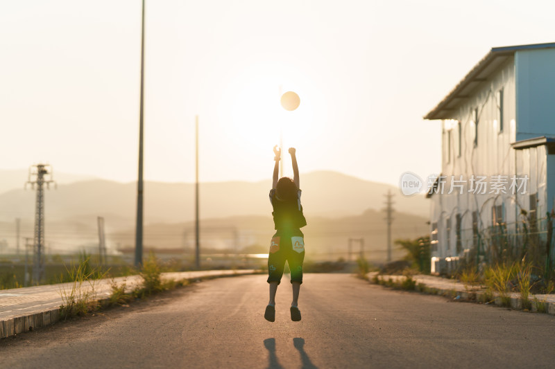户外女孩夕阳下跳跃抛球