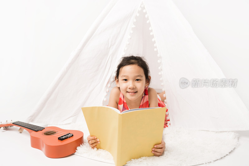 趴在白色帐篷里读书的女孩