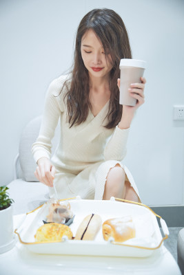 在烘焙店吃面包喝牛奶的可爱亚洲少女