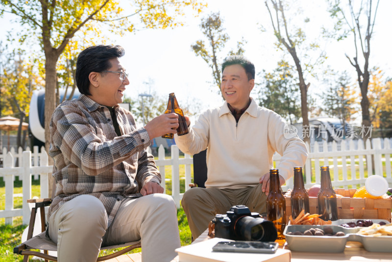 两个老年男人坐在露营地喝啤酒