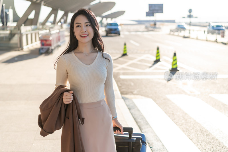 商务女士在机场拉着行李箱