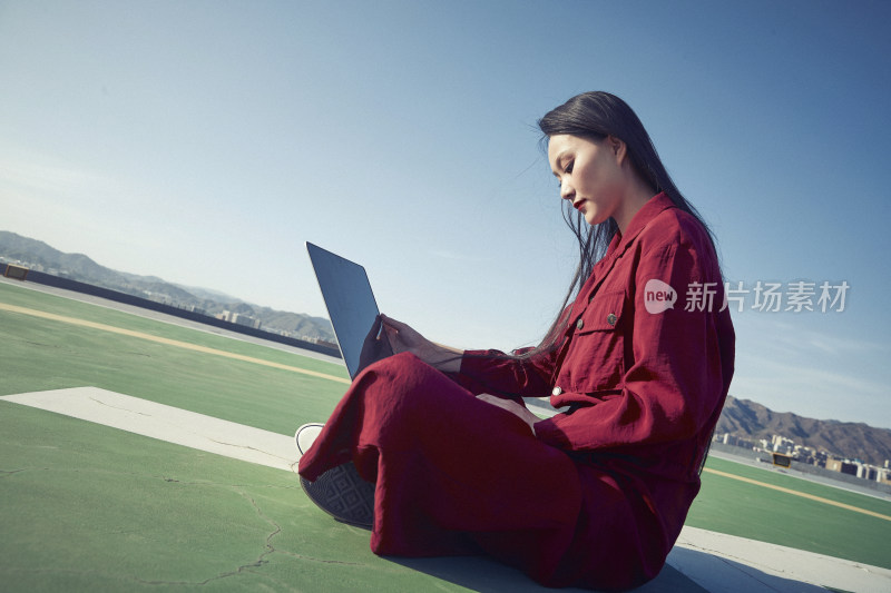 亚洲商务年轻女性在楼顶停机坪使用电脑办公