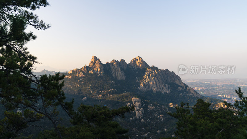 山间树木环绕的巍峨险峻的山峰