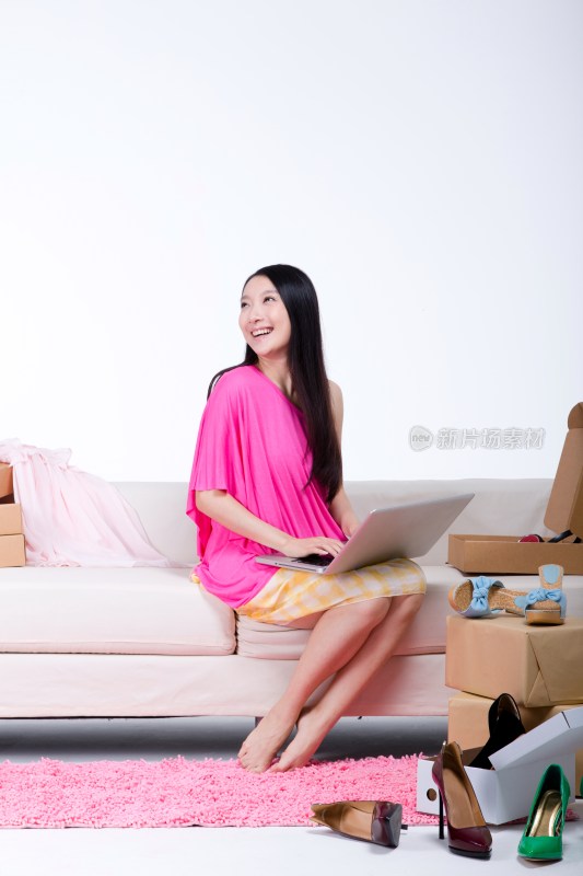 棚拍年轻女人坐在沙发上使用笔记本电脑上网购物