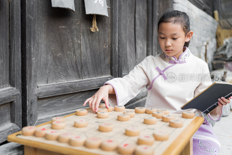 穿中国传统服饰下中国象棋的中国女孩