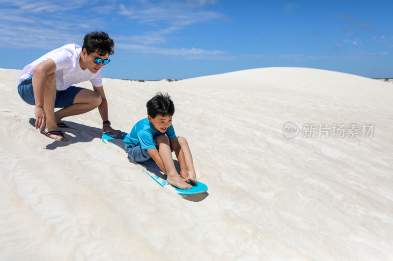 在白沙漠上玩滑板的中国父子