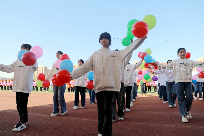 学生在操场手持气球列队行进