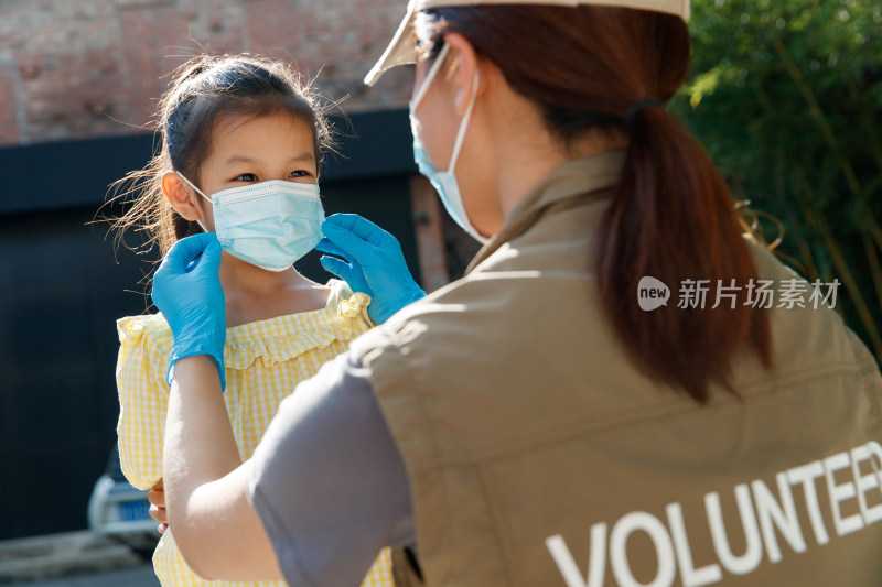 社区志愿者帮小女孩戴口罩