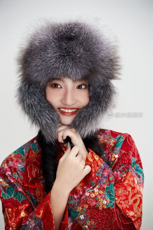 白色背景下穿中国传统服饰头戴绒帽的少女