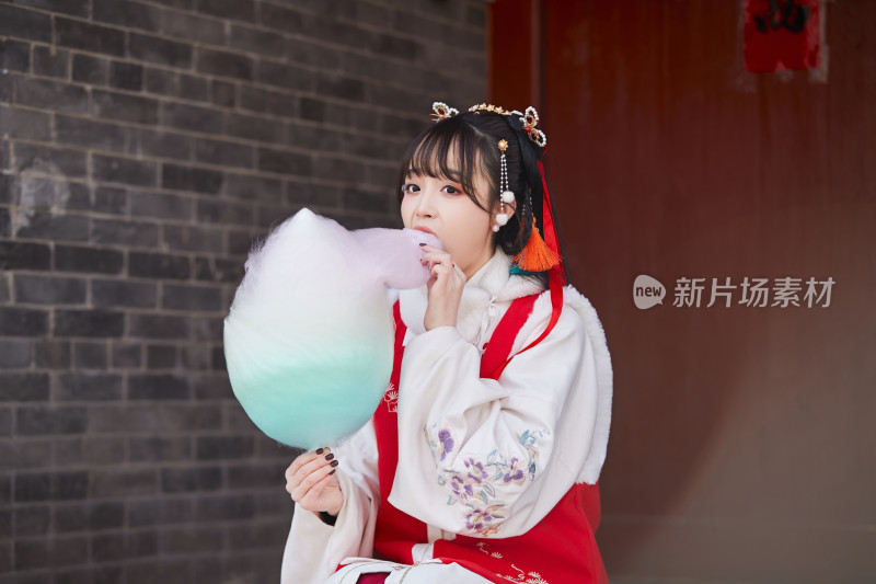 身穿喜庆汉服吃棉花糖的少女