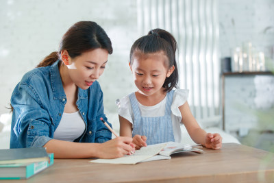 辅导女儿做作业的青年女人