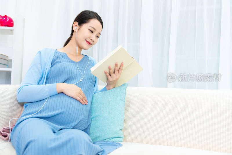 年轻孕妇在沙发上看书