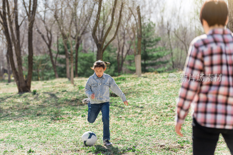 初春在公园草坪上踢足球的中国母女