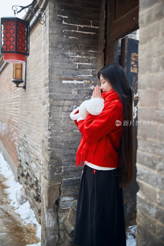 雪后在老城古巷穿着喜庆服饰的亚洲少女