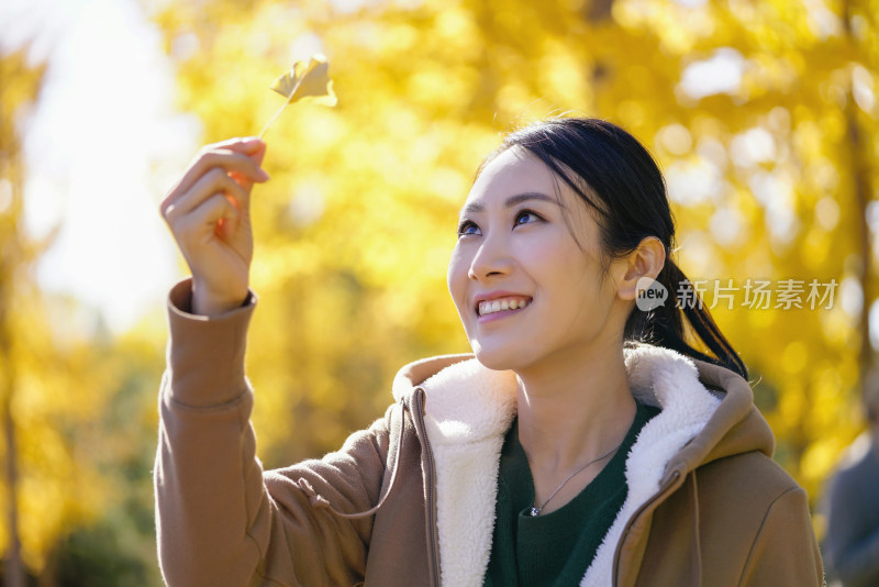 快乐的年轻女子手拿银杏叶