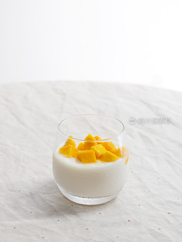 白色桌面上的一杯芒果布丁饮品