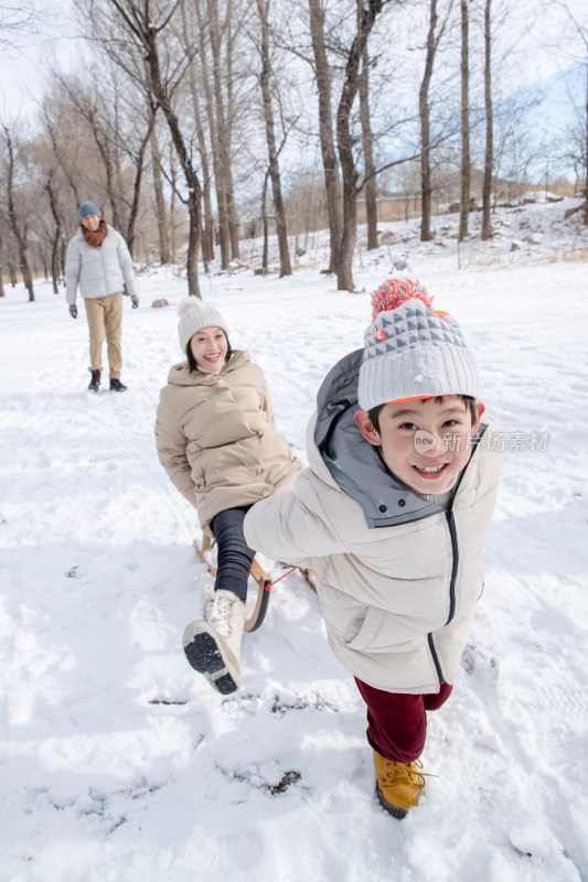 在雪地上玩雪橇的一家人