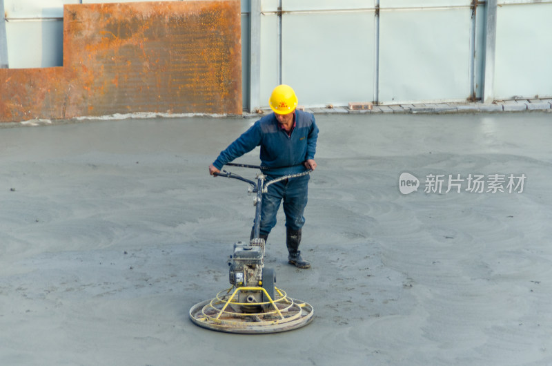 建筑工地上，工人使用路面抹平机平整路面