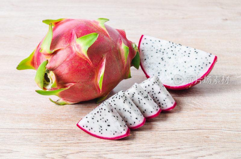 木桌上完整及切片的火龙果