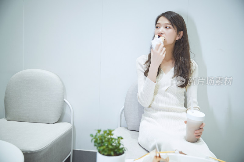 在烘焙店吃面包喝牛奶的可爱亚洲少女