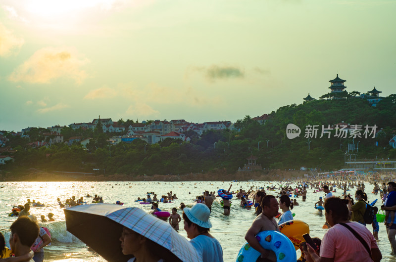 青岛汇泉湾夕阳下，海水浴场中的人们