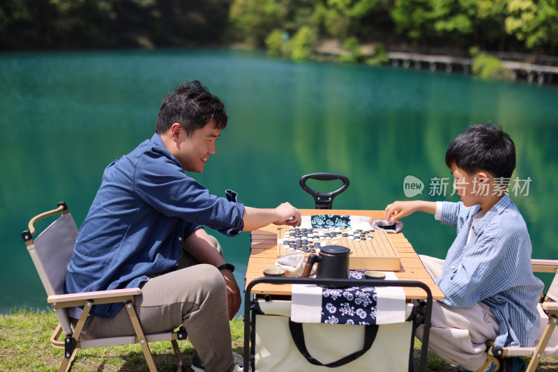 在湖边下棋的父子