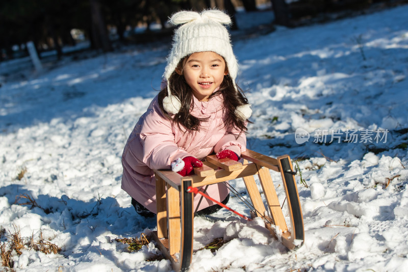 快乐的小女孩在雪地上玩雪橇