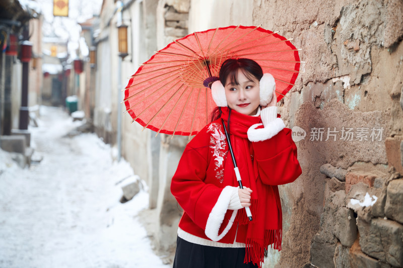 雪后在老城古巷穿着喜庆服饰的亚洲少女