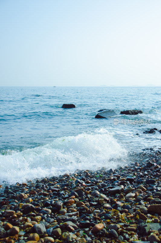 海浪轻抚冲刷岸边鹅卵石海滩